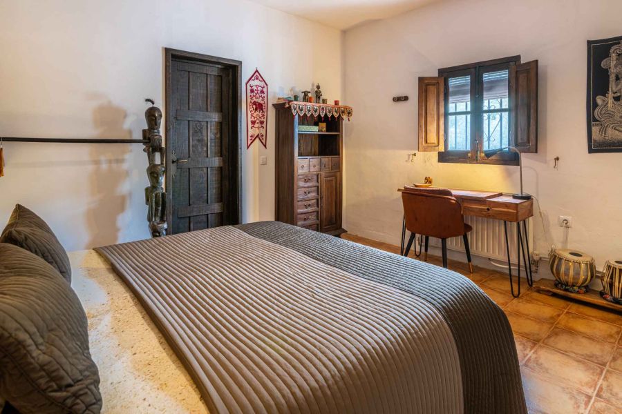 tweepersoonbed in ruime kamer  met schrijftafel en zicht op olijfgaard